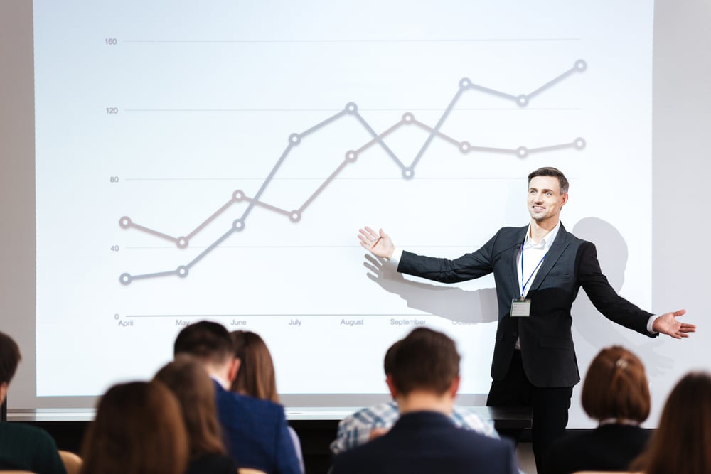 Smiling charismatic speaker giving public presentation in conference hall