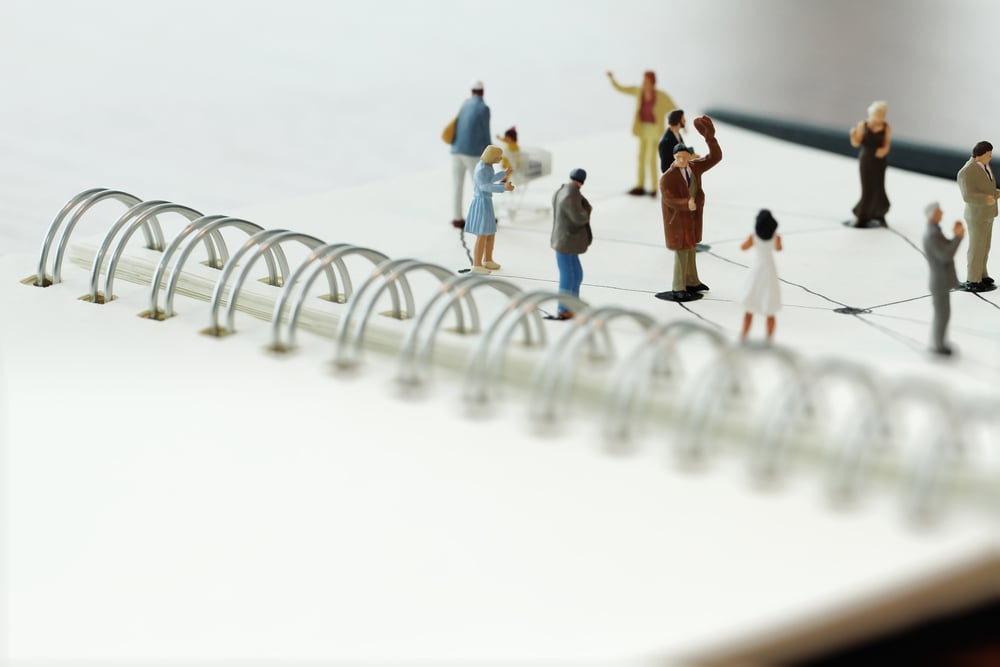 close up of miniature people with social network diagram on open notebook on wooden desk as social media concept